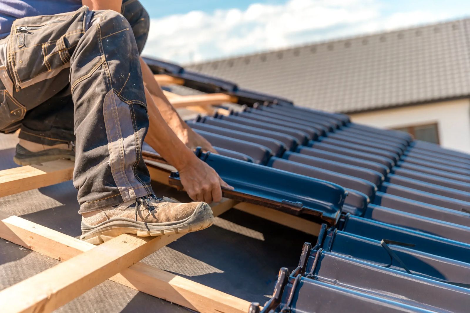 Roofer replacing broken concrete roof tiles on a pitched roof